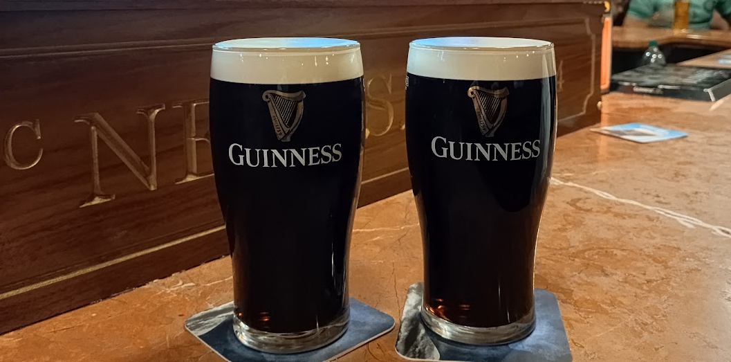 Two pints of Guinness on the wooden counter of a Dublin pub